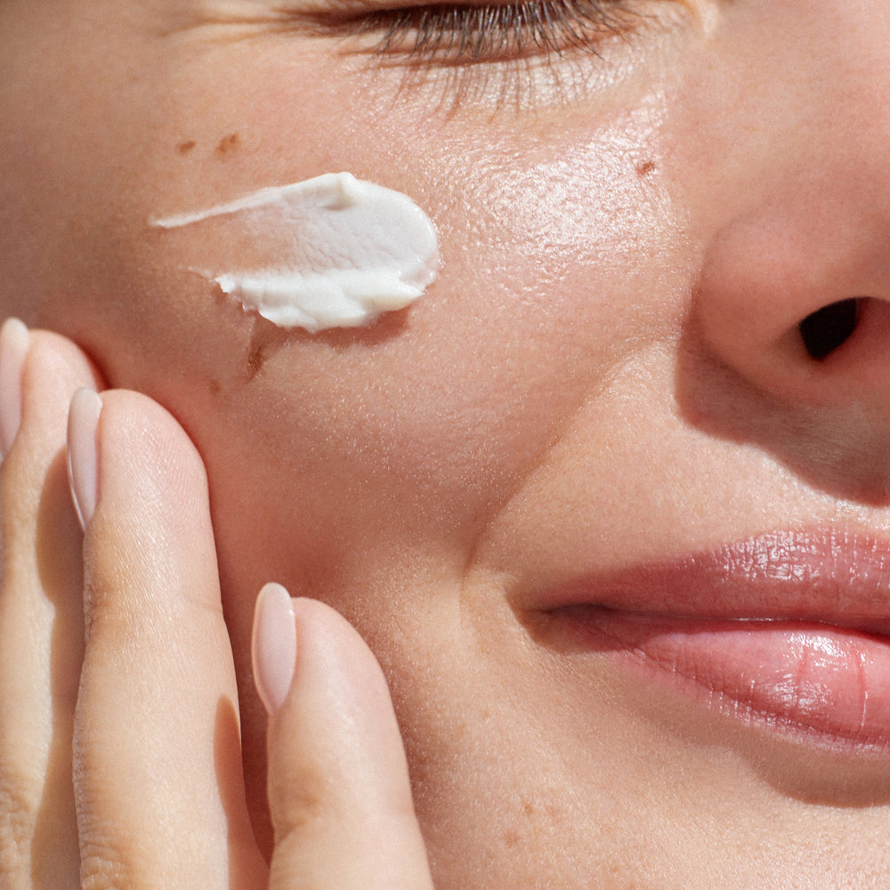 Close-up of a woman applying cream to her face
