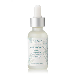 A clear glass bottle with a dropper cap containing Moringa Face Oil, labeled for repair and replenish.