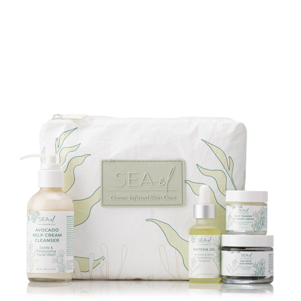 A collection of skincare products including a bottle of Matcha Oil, a Facial Cleanser, a jar of Night Cream, and a Sea Kelp Mud Mask, all arranged in front of a white bag decorated with green seaweed illustrations.