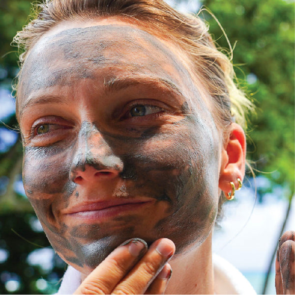 Image of a girl outside, wearing our Sea Kelp Mud Mask on her face with a big smile.