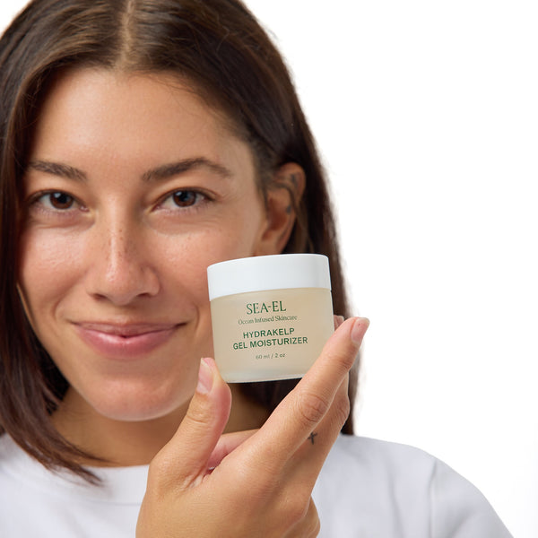 A woman holding a jar of SEA-EL Hyalukeep Gel Moisturiser against a clean white background.