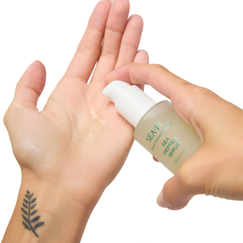 A hand holding a small bottle of SPA E facial serum while another hand receives the clear gel, shown against a plain white background.