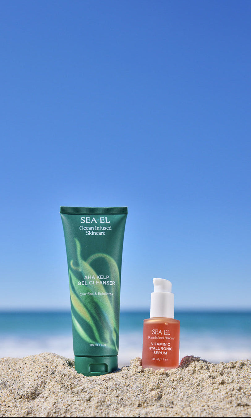 picture of our cleanser and serum sitting on the sand at the beach.