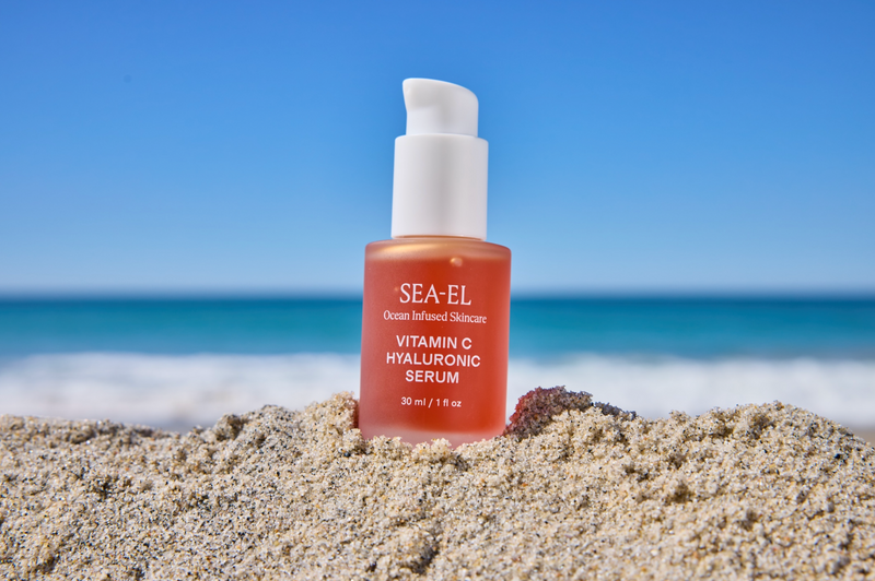 image of our Vitamin C Hyaluronic Serum in the sand at the beach