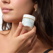Woman holding a jar of Kelp Tamanu Oil Night Cream close to her face